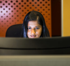 Una mujer sentada frente a un monitor de computadora con un fondo de puntos coloridos