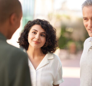 Tres personas conversan en el exterior