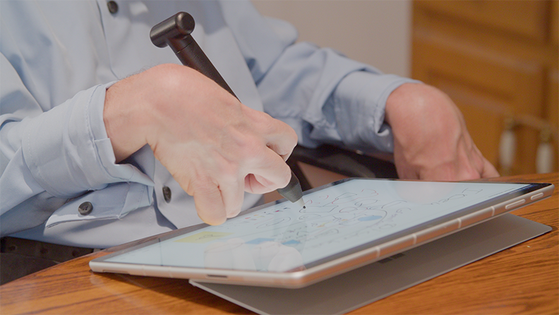 Dave Dame usando el lápiz para Surface con empuñadura negro para tomar notas en su Surface Go.