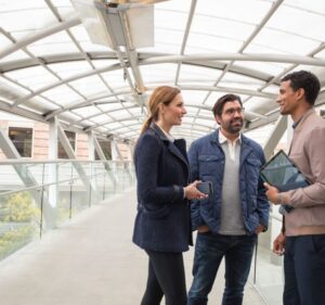 Tres personas hablan en un corredor techado