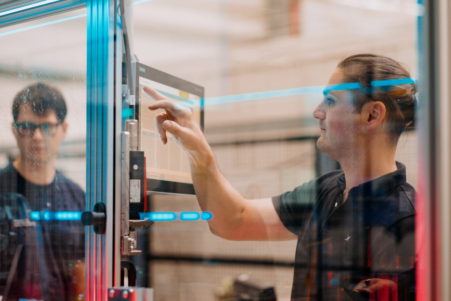 Paul Kempt, à esquerda, programador da thyssenkrupp, com Marcus Schoenherr, engenheiro da thyssenkrupp, trabalham na máquina de teste de células de bateria EV na fábrica em Chemnitz, Alemanha. Foto de Anastasia Pivovarova para a Microsoft