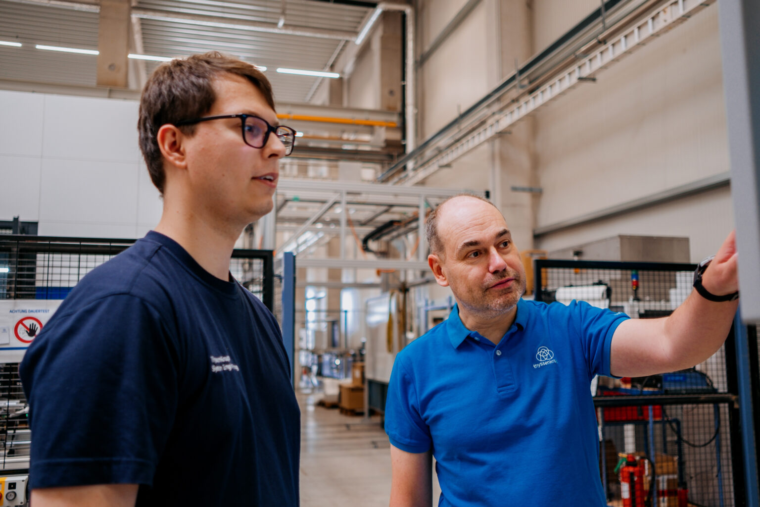 Paul Kempt, à esquerda, programador da thyssenkrupp, com Marcel Pfeiffer, diretor de soluções de fábrica digital da empresa, na fábrica em Chemnitz, Alemanha. Foto de Anastasia Pivovarova para a Microsoft
