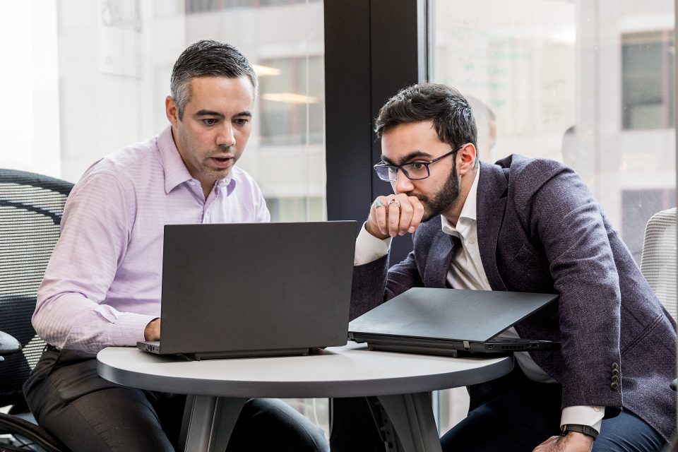 dois homens de terno olham para um computador
