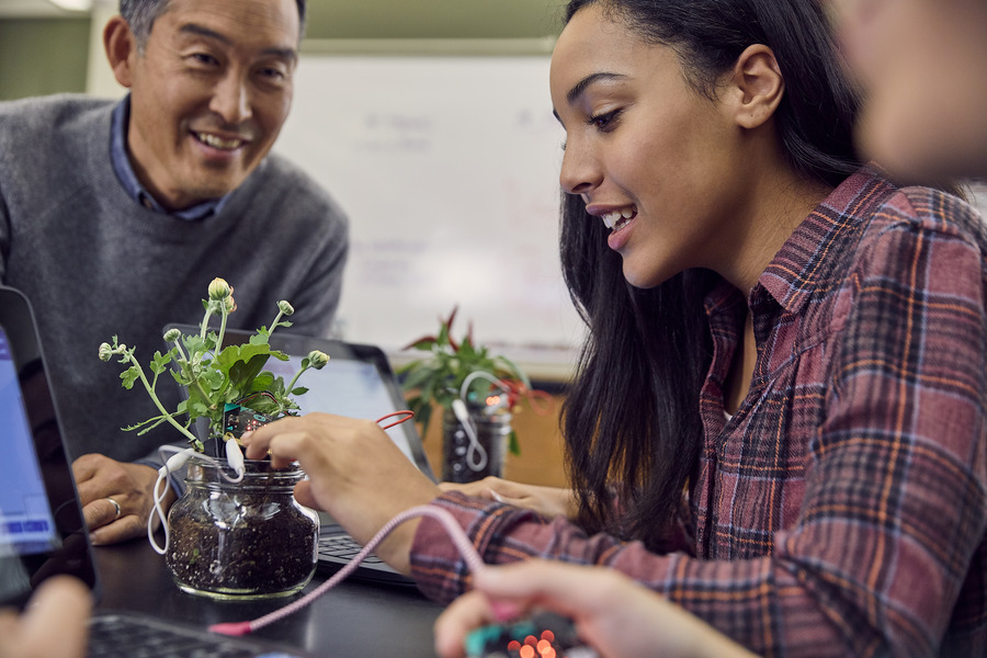 Una estudiante y un profesor observan una planta