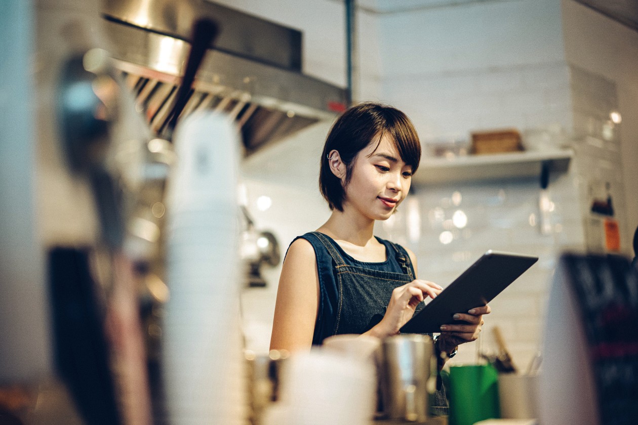 Retrato de una joven barista que usa una tableta digital en una cafetería