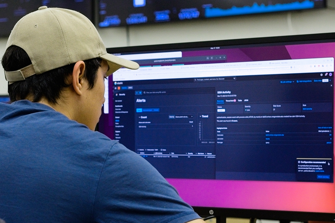 Estudiante trabaja frente a un monitor de gran tamaño en el centro de operaciones de seguridad de la Universidad Estatal de Oregon