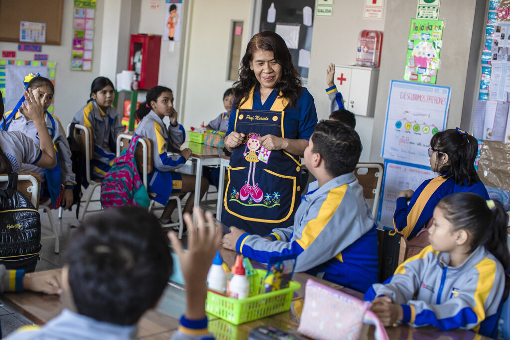 Una maestra está de pie entre estudiantes en un aula