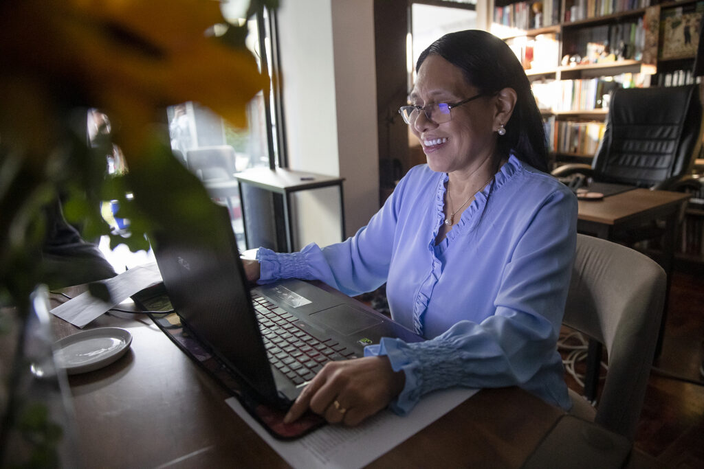 Uma mulher em um escritório sentada em uma mesa trabalhando em um laptop