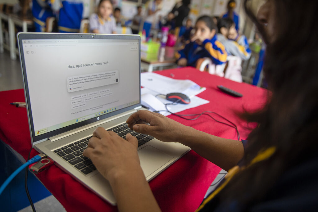 Uma mulher está sentada em uma mesa trabalhando em um laptop com uma sessão do Copilot exibida