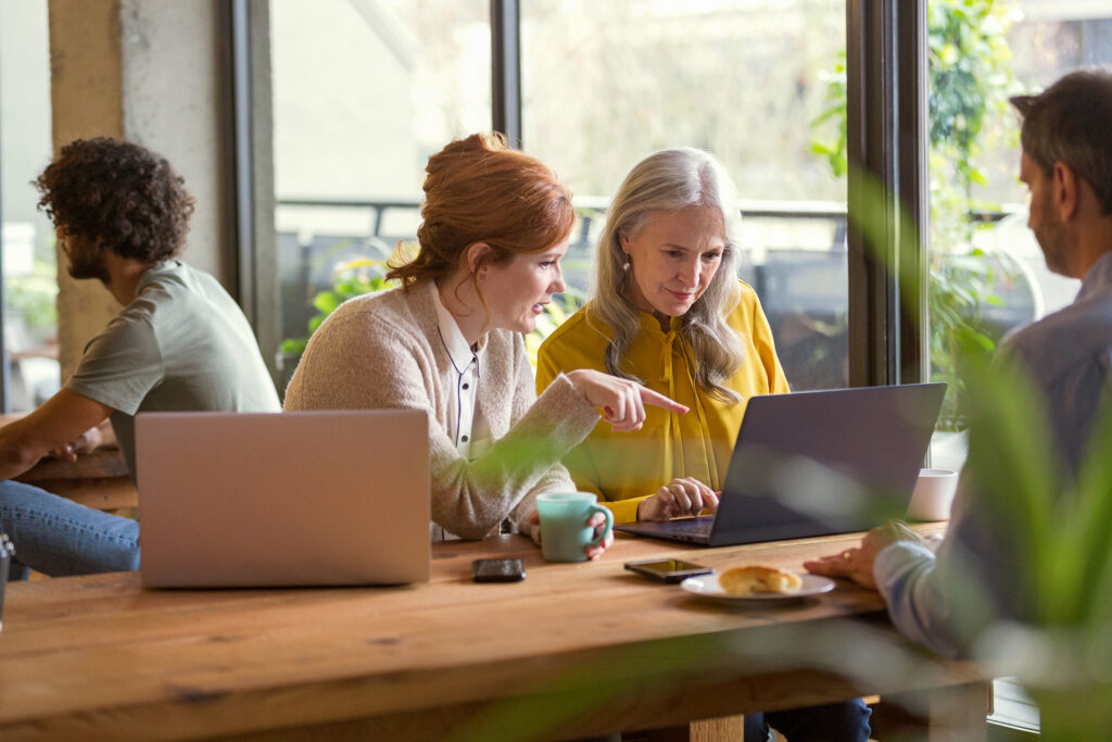 Cuatro personas en una oficina trabajan con sus laptops