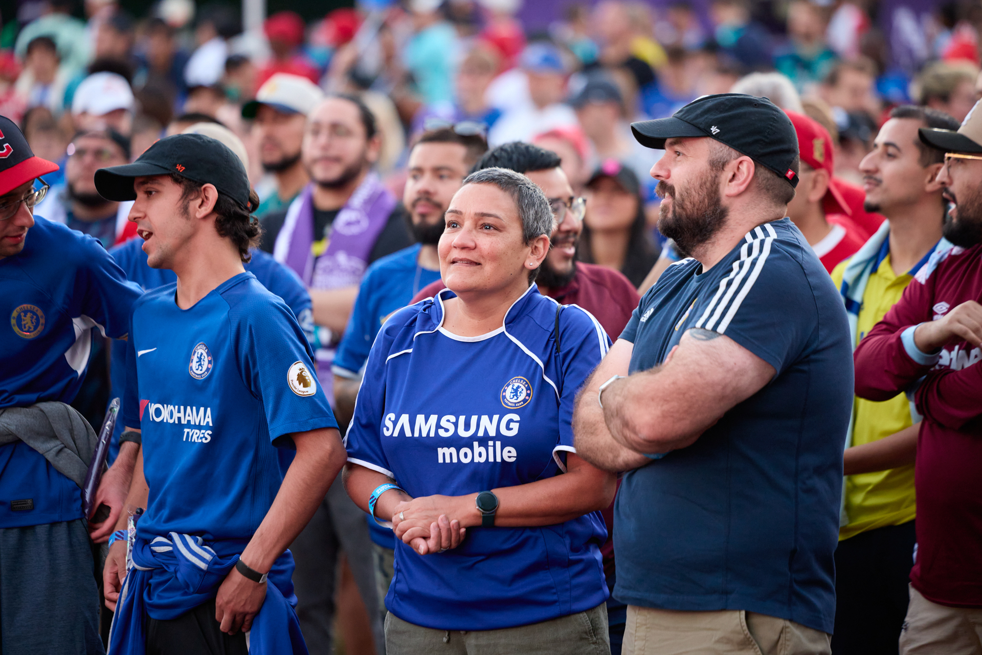 Fanáticos reunidos en un evento al aire libre. Tres usan jerseys de Chelsea