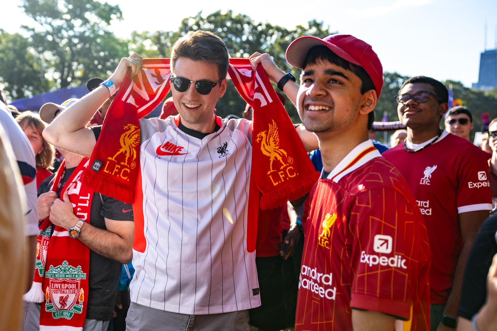 Dos aficionados al Liverpool observan a la distancia. Uno usa una bufanda y el otro una gorra roja