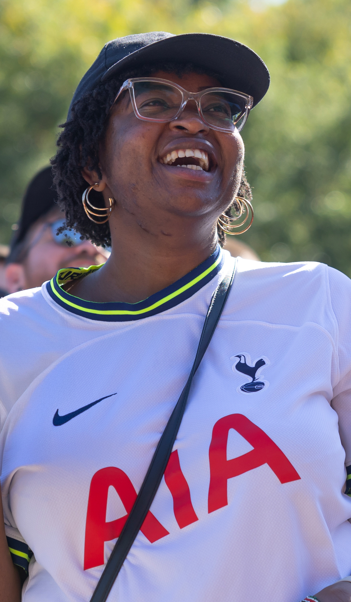 Mujer sonriente usa un jersey del Tottenham con las letras AIA al frente