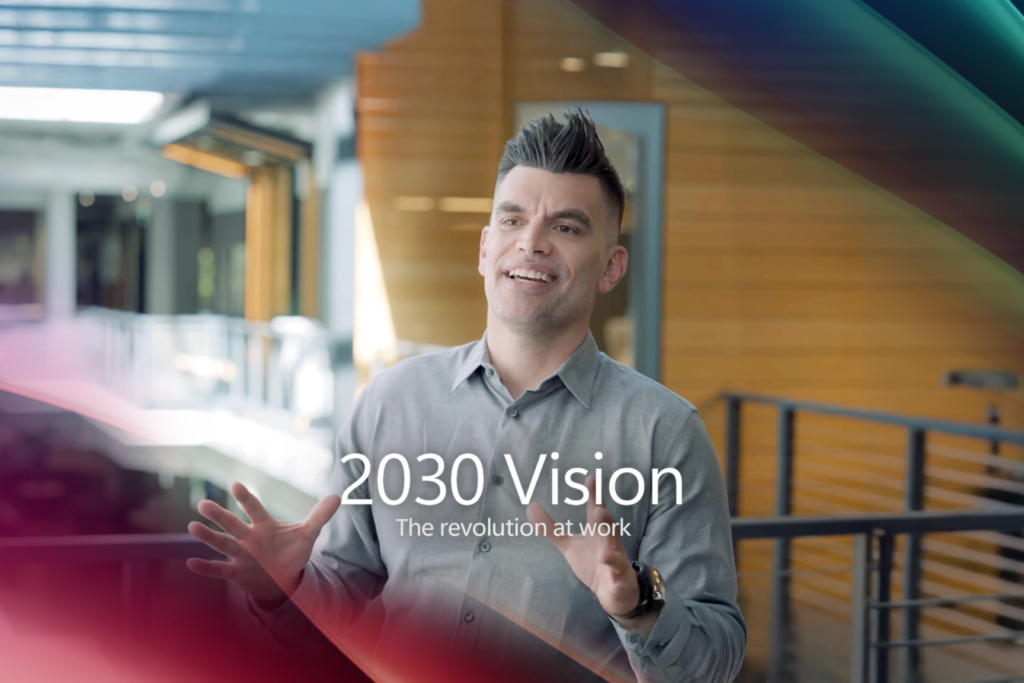 Un hombre habla a la cámara con el texto "2030 vision, the revolution at work" sobrepuesto